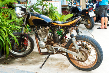 Old rusty motorcycle. typical vehicle in Asia. A crumbling motorcycle in a parking lot near a cafe