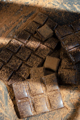 pieces of dark chocolate sprinkled with cocoa powder on a dark background