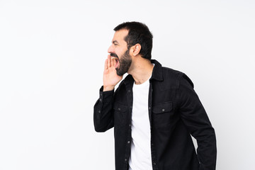 Fototapeta premium Young man with beard over isolated white background shouting with mouth wide open to the lateral