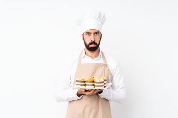 Young man holding muffin cake over isolated white background with sad and depressed expression