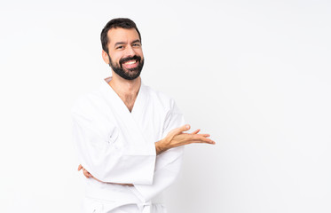 Young man doing karate over isolated white background presenting an idea while looking smiling towards © luismolinero