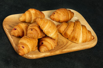 homemade croissants on a kitchen board and a dark surface