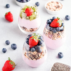 Chia seeds pudding with granola, blueberry and strawberry in glasses. Yogurt with chia seeds, berries, kiwi and muesli for healthy breakfast, copy space
