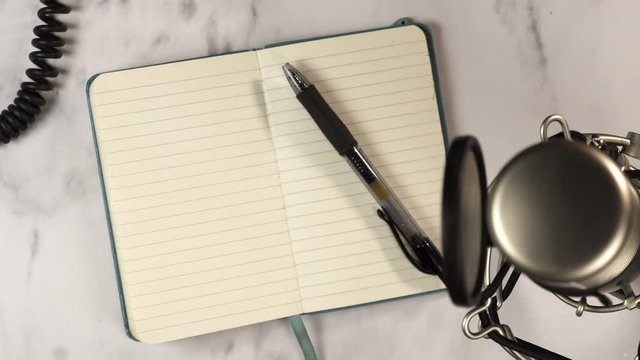 Professional microphone with notebook and pen from top view.