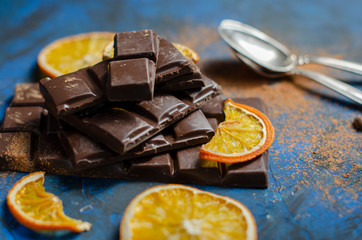 a slice of dark chocolate in cocoa powder with dried oranges