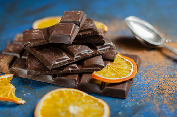 a slice of dark chocolate in cocoa powder with dried oranges