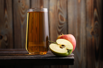 A glass of fresh apple juice to quench your thirst, with a red and green apple on the edge of the...