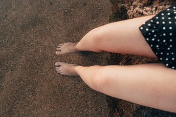 Legs of a young woman relaxing with her feet in the water on the shore of the mediterranean sea