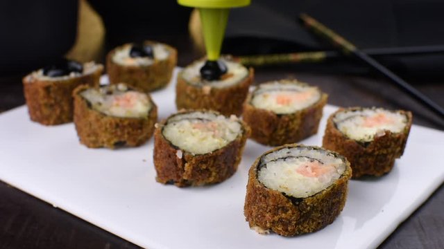 Pouring tare sauce in salmon fish hot rolls