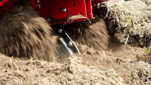 Tiller engine working in garden in 4K VIDEO. Cultivator machine cultivating field at spring. Extreme close-up of soil throwing away of blades. Modern farming, technology agriculture. Close-up.