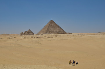 エジプトカイロのピラミッドと砂漠を進むラクダと人