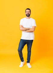 Fototapeta na wymiar Full-length shot of man with beard over isolated yellow background with glasses and happy