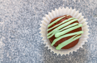 Truffle of dark and milk chocolate with mint (wasabi, green tea, pistachio) close-up on a grey concrete background. Selective focus, top view, copy space