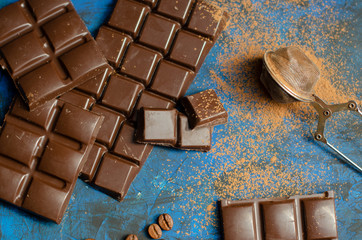 bar of dark chocolate on a blue background with sprinkled cocoa