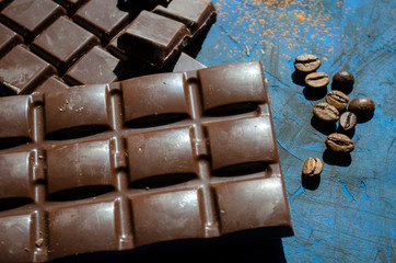 bar of dark chocolate on a blue background with sprinkled cocoa