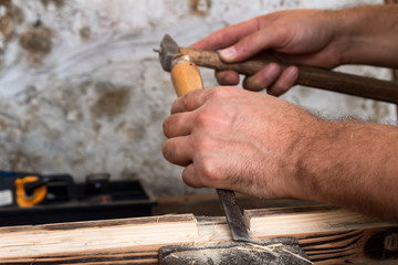 Male carpenter working on old wood in a retro vintage workshop.