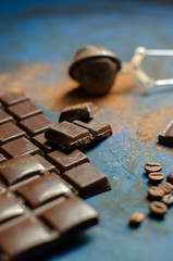 bar of dark chocolate on a blue background with sprinkled cocoa