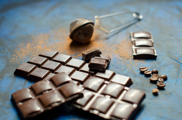 bar of dark chocolate on a blue background with sprinkled cocoa