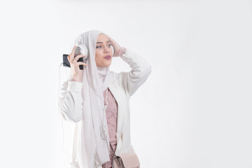 Muslim girl with headscarf isolated on white background listening music on her phone