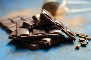 bar of dark chocolate on a blue background with sprinkled cocoa