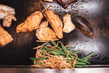 Fish fillets and mussels cooking on a hot griddle