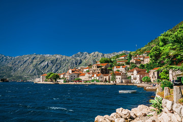 The coastal old town of Perast is a tourist attraction in Montenegro. Old buildings with red roofs on the mountainside.