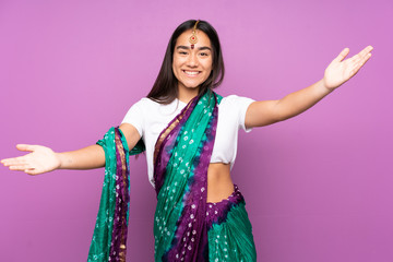 Young Indian woman with sari over isolated background presenting and inviting to come with hand