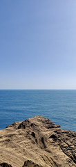 Vertical landscape of onlooking blue ocean from a rocky dusty cliff