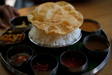 A South Indian rice plate thali with papad and lots of spicy side dishes