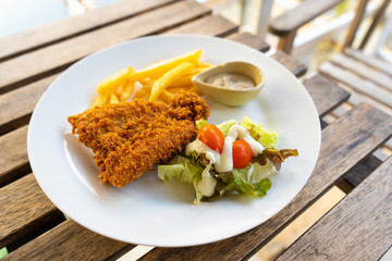Dish Fish in batter with french fries. Fish on a plate with potatoes and salad in a summer cafe.