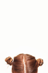 Head of a girl with two messy twisted curled red hair buns on white background. Creative hairstyle. Copyspace.