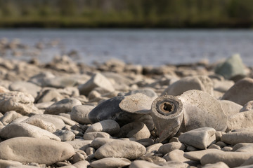 Broken motor for a boat lies on a rocky riverside