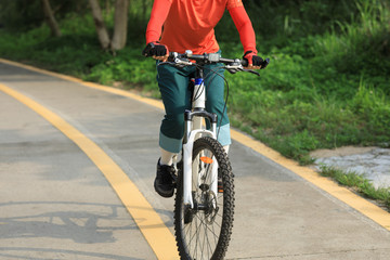 Woman cyclist riding a bike on sunny park trail in spring