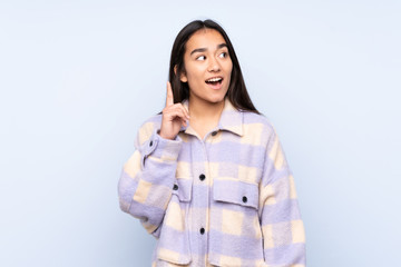 Young Indian woman isolated on blue background thinking an idea pointing the finger up