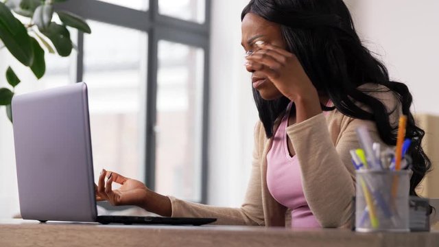 remote job, technology and people concept - tired or stressed african american young woman with laptop computer working at home office