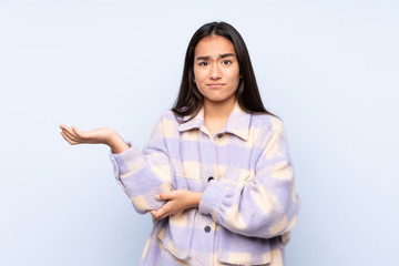 Young Indian woman isolated on blue background unhappy for not understand something