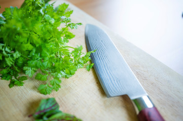 fresh herbs with damask knife on a wooden board ready to cut