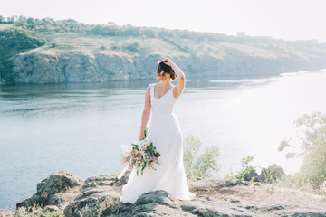 Bride in a luxurious white wedding dress in nature at sunset