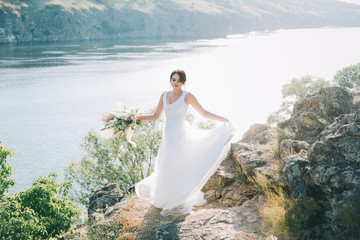 Bride in a luxurious white wedding dress in nature at sunset