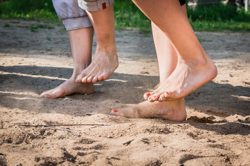Fototapeta na wymiar A man and a woman with bare feet stomp on the sand barefoot
