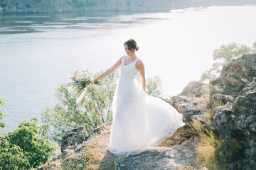 Bride in a luxurious white wedding dress in nature at sunset