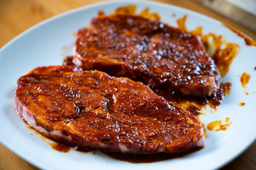 fresh neck steak of pork marinated with paprika and oil with fresh herbs on top ready to grill