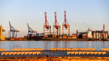 The cranes in the port of Odessa at sunset with the moon in the background.