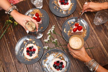 Bachelorette party, girls hands with drinks and sweet cakes with summer berries on a wooden table. Party, sweet table. Summer offer desserts in the restaurant.