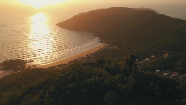 Drone aerial sunrise view over mountain by the beach, Morro Do Macaco, Bombinhas, Santa Catarina, Brazil