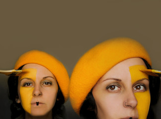 Portrait of two female twins with yellow hats, painting their faces in yellow color with paint...