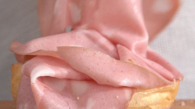 Preparation of a sandwich with mortadella, close-up view, hands working with bread and salami.