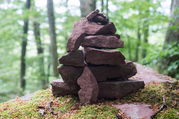 Closeup of stone balance on big rock covered by the moss in a forest