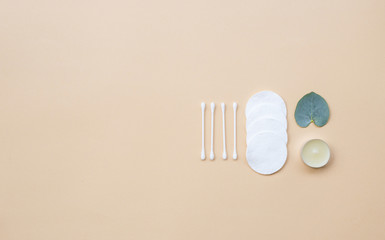 Cotton pads and fresh eucalyptus leaves on a beige background. Flat lay, top view, copy space. Women's health care