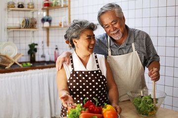 Naklejka premium Happiness senior elderly couple having fun in kitchen with healthy food for working from home. COVID-19